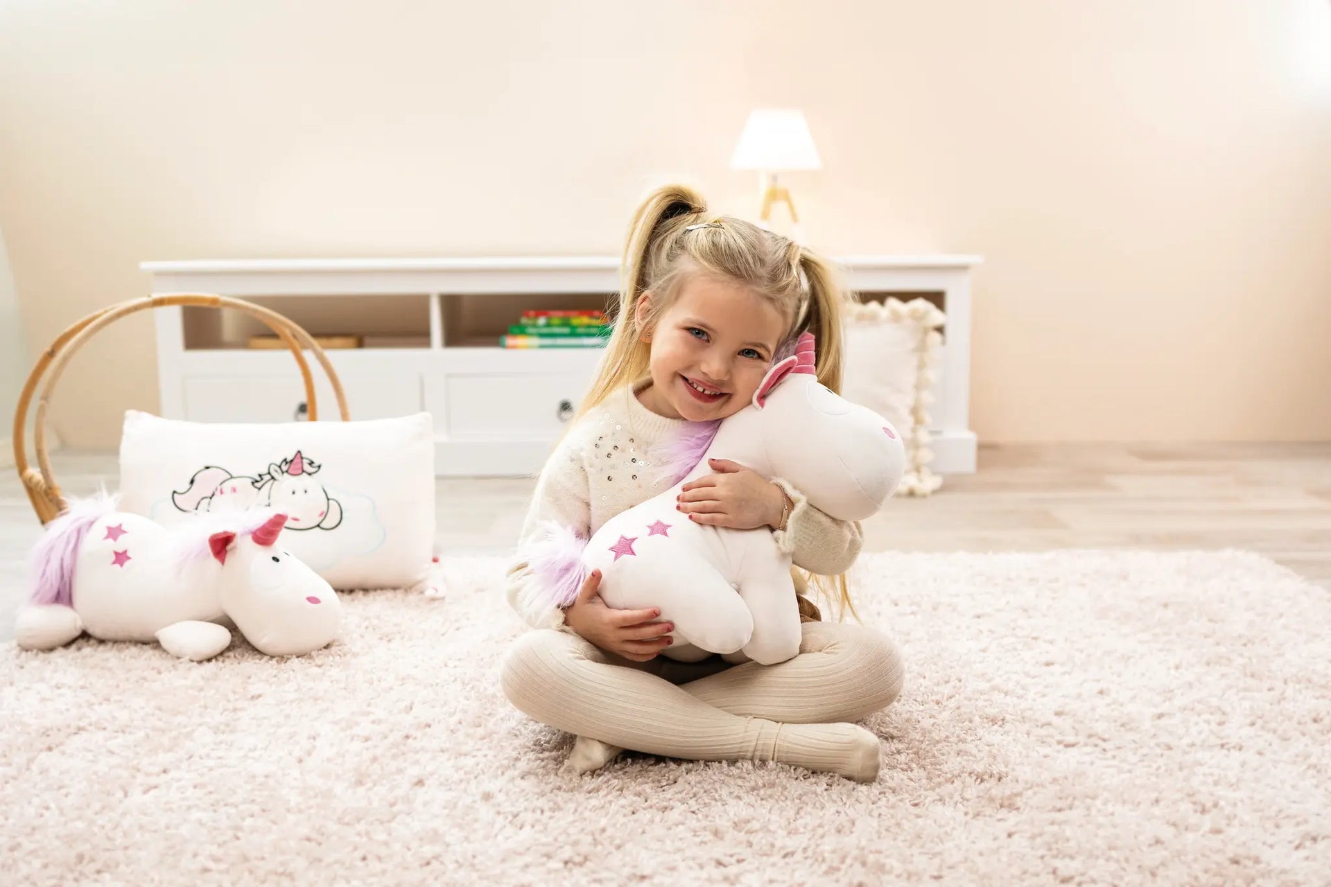 Kleines Mädchen sitzt im Kinderzimmer und umarmt ein Kuscheltier – weiches Plüschtier für Babys und Kinder