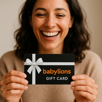 Lachende Frau hält einen BabyLions Geschenkgutschein mit schwarzem Hintergrund und weißer Schleife – perfekt zum Verschenken für Geburt, Taufe oder besondere Anlässe.