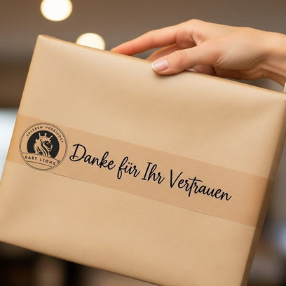 Hand hält nachhaltiges Paket mit BabyLions-Logo und Aufschrift Danke für Ihr Vertrauen.