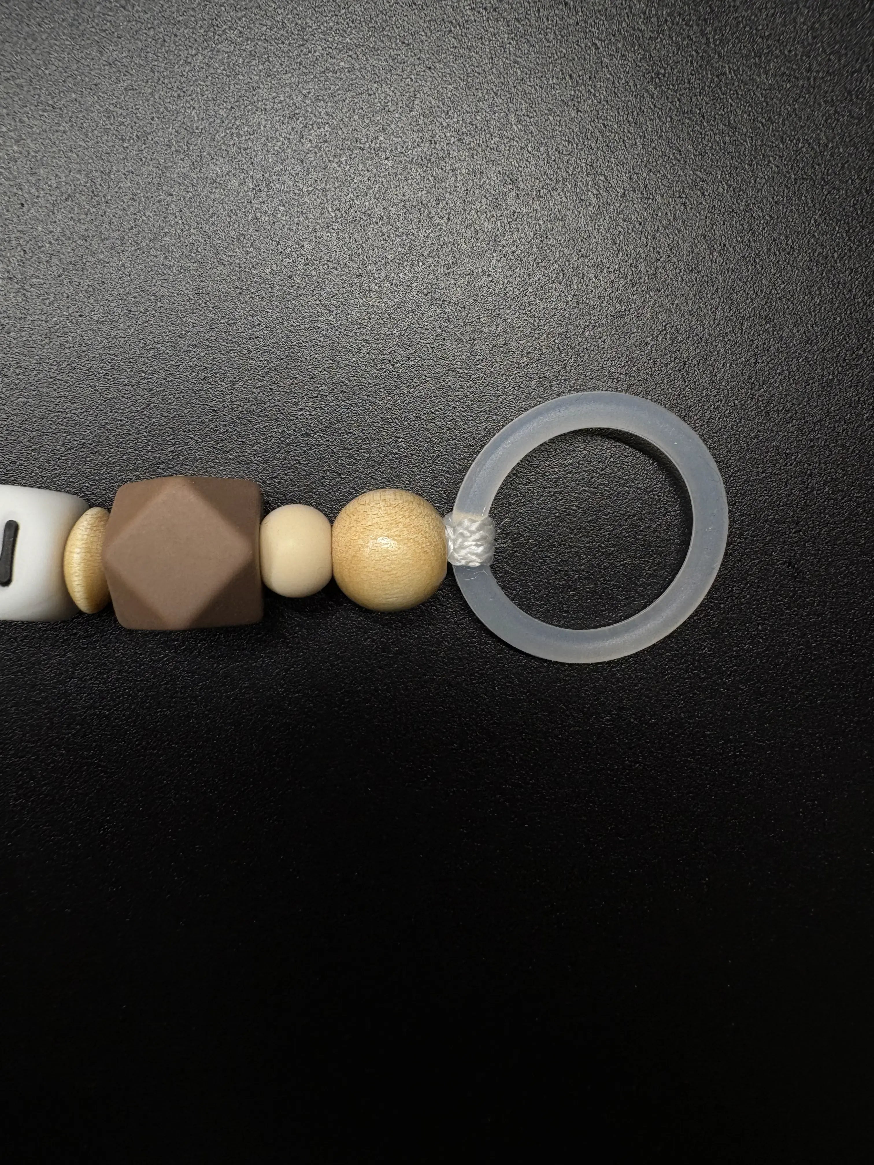 Nahaufnahme des Silikonrings der personalisierten Schnullerkette Bär mit Namen von BabyLions® mit brauner Silikonperle, Holzperlen und hochwertigem Schnulleradapter
