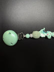 Seitenansicht der personalisierten Schnullerkette Dino mit Namen von BabyLions® mit Dino-Motiv, gehäkelter Perle, Holzclip und hochwertigen Silikon- sowie Holzperlen in Mint