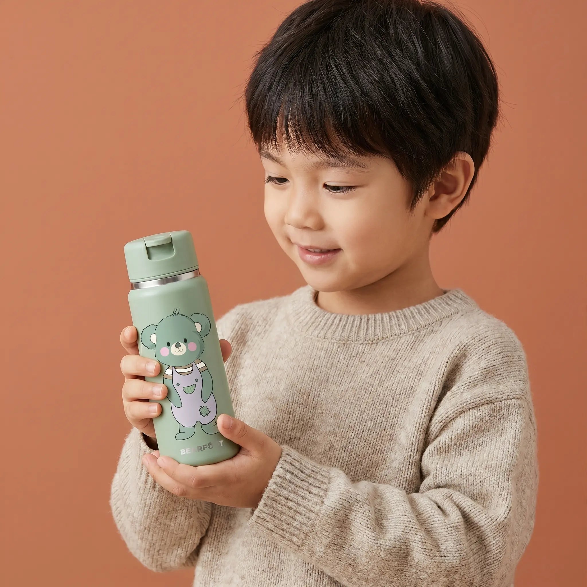 Kind hält TINY Thermo Kinder Trinkflasche Koala 200 ml aus Edelstahl in Salbeigrün – BPA-freie, auslaufsichere Isolierflasche mit Strohhalm für Kindergarten, Ausflüge und unterwegs