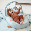 Baby liegt im Babynest mit Spielbogen und Greifspielzeug – Aktivitätsspielzeug für Babys mit Rassel und Spiegel in Blau