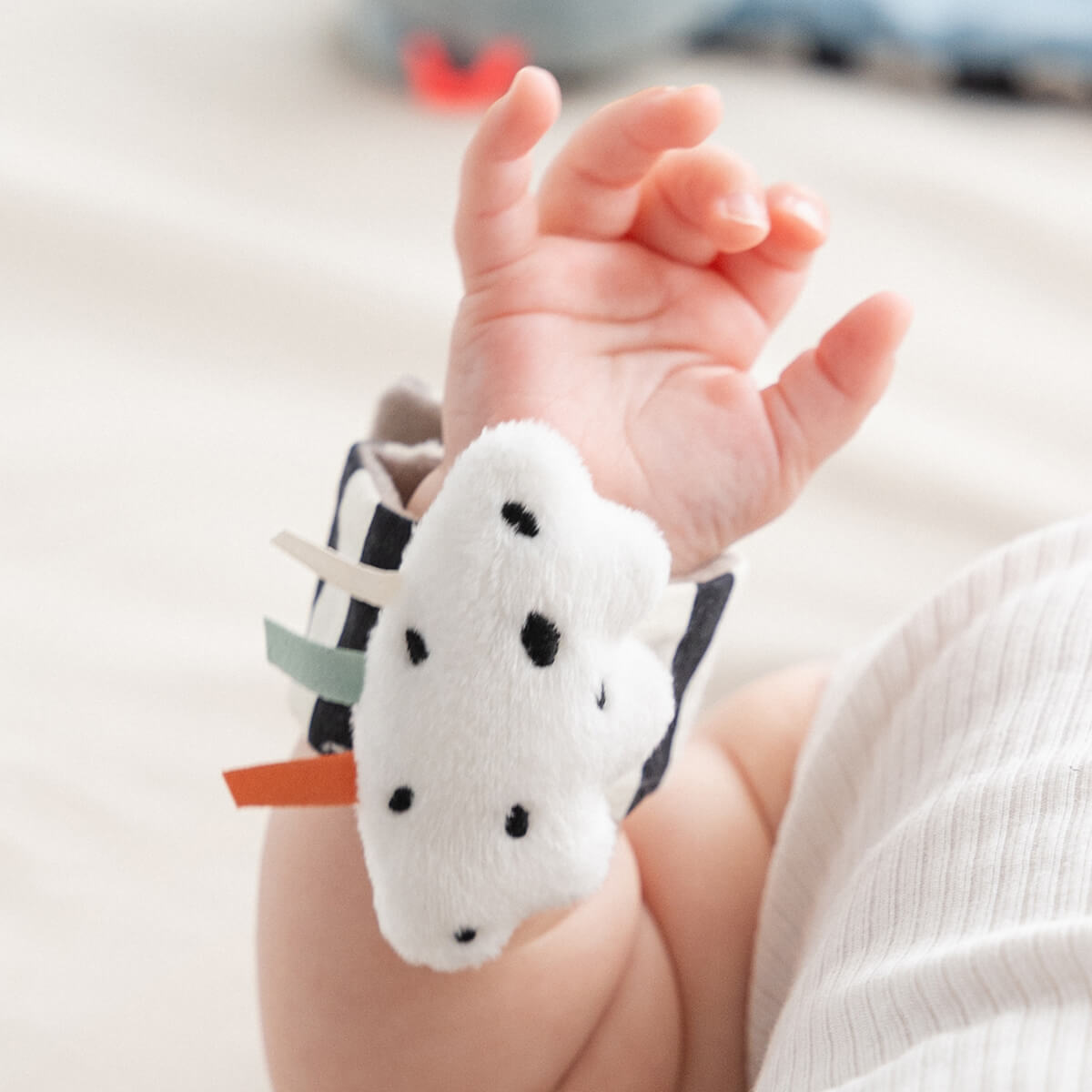 Baby trägt Rasselarmband mit Wolkenmotiv am Handgelenk