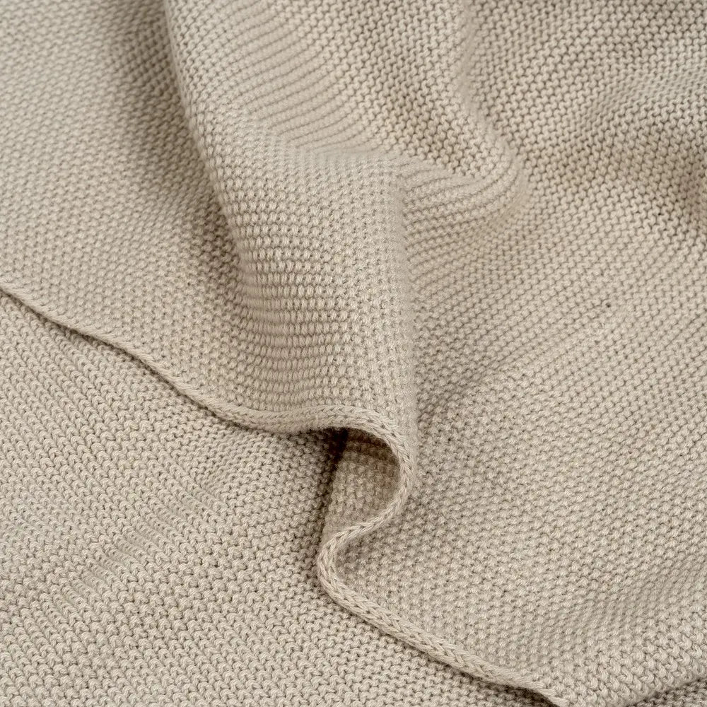 Nahaufnahme der beigen Babydecke aus 100 % Baumwolle mit feiner Strickstruktur und weicher Oberfläche – Detailansicht des Stoffes.