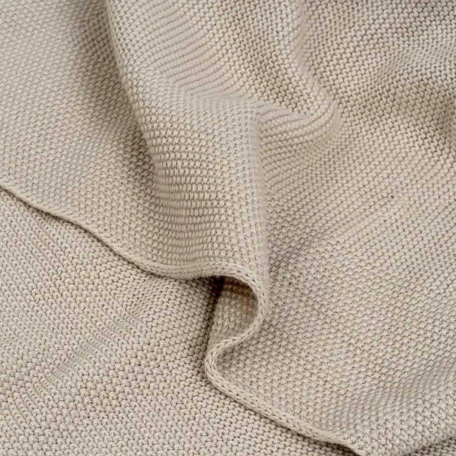 Nahaufnahme der beigen Babydecke aus 100 % Baumwolle mit feiner Strickstruktur und weicher Oberfläche – Detailansicht des Stoffes.