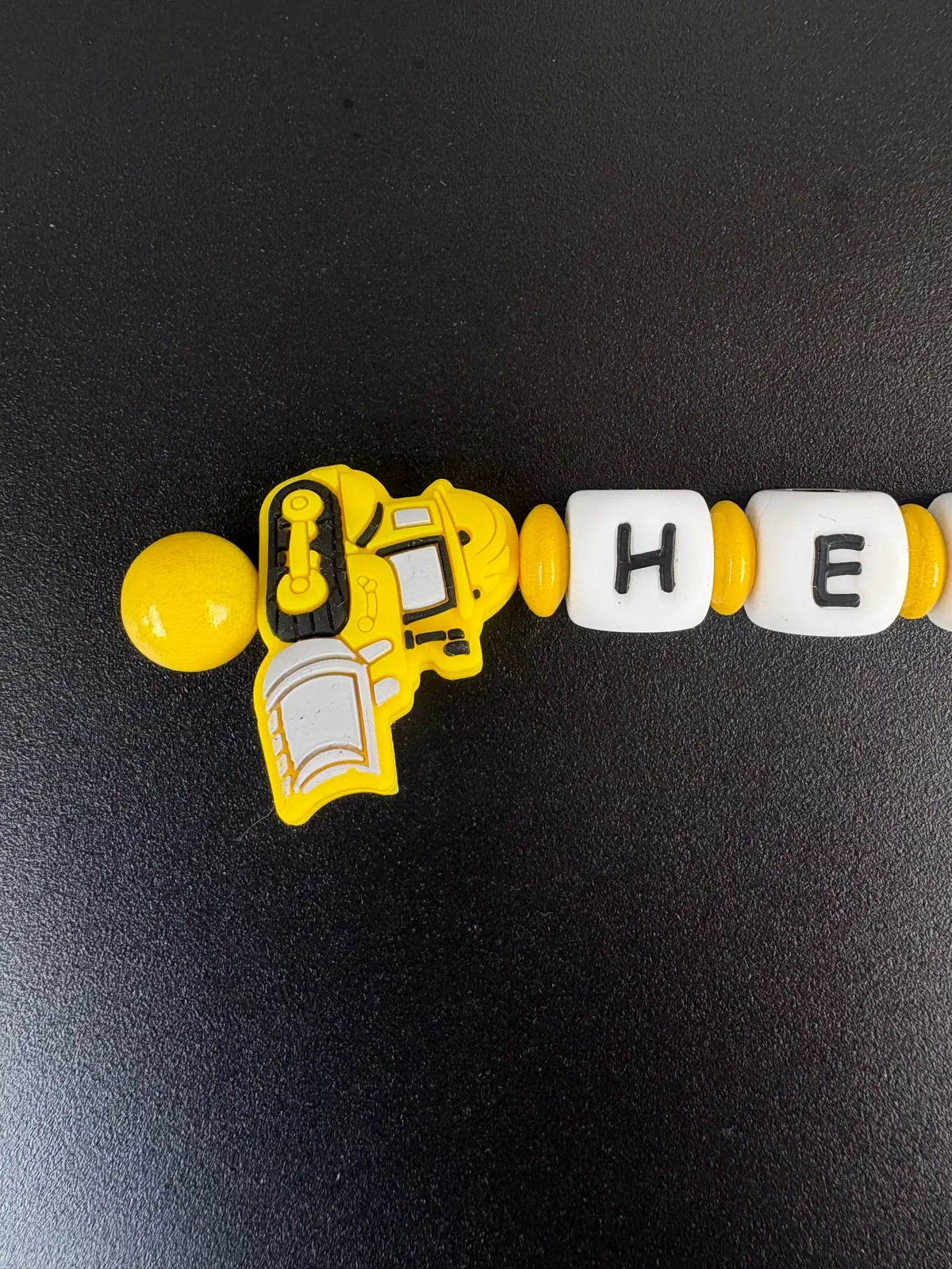 Detailansicht personalisierter Schlüsselanhänger mit gelbem Bagger-Motiv und Buchstabenperlen – handgefertigt von BabyLions®