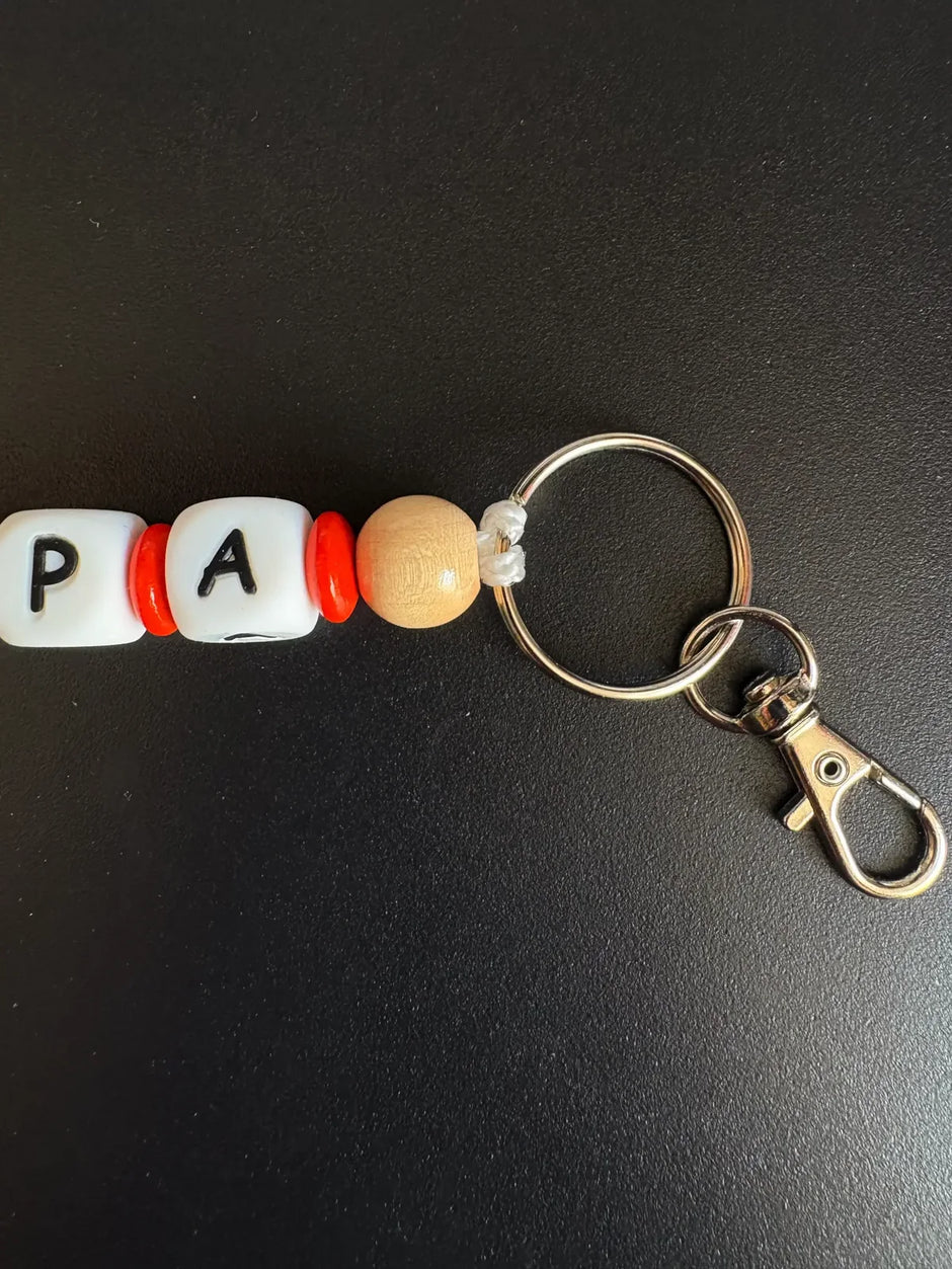 Detailansicht des personalisierten BabyLions Schlüsselanhängers PAPA mit Holzperle, Schlüsselring und Karabiner