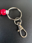 Detailansicht des LOVE Schlüsselanhängers mit roter Perle, Metallring und Karabiner von BabyLions®