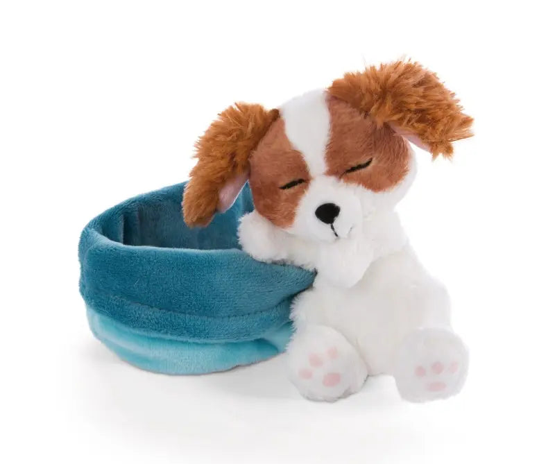 Sleeping Pets Cocker Spaniel Welpe mit braun-weißem Plüschfell und geschlossenen Augen, sitzend neben seinem blauen Kuschelkörbchen.