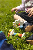 Goki Greifling Stielrassel Regenbogen aus Holz beim Spielen im Gras