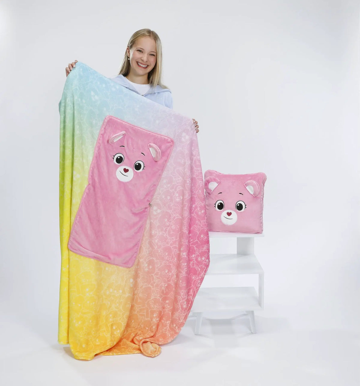 Ausgebreitete Kinder-Kuscheldecke mit Farbverlauf in Blau, Rosa, Orange und Gelb sowie integriertem rosa Bärenkissen