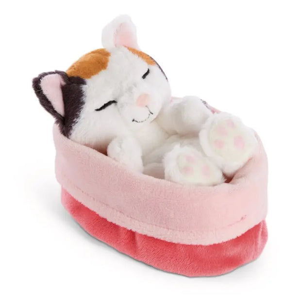 NICI Sleeping Pets Glückskatze mit dreifarbigem Fell und geschlossenen Augen, schlafend im kuschelweichen rosa Plüschkörbchen.