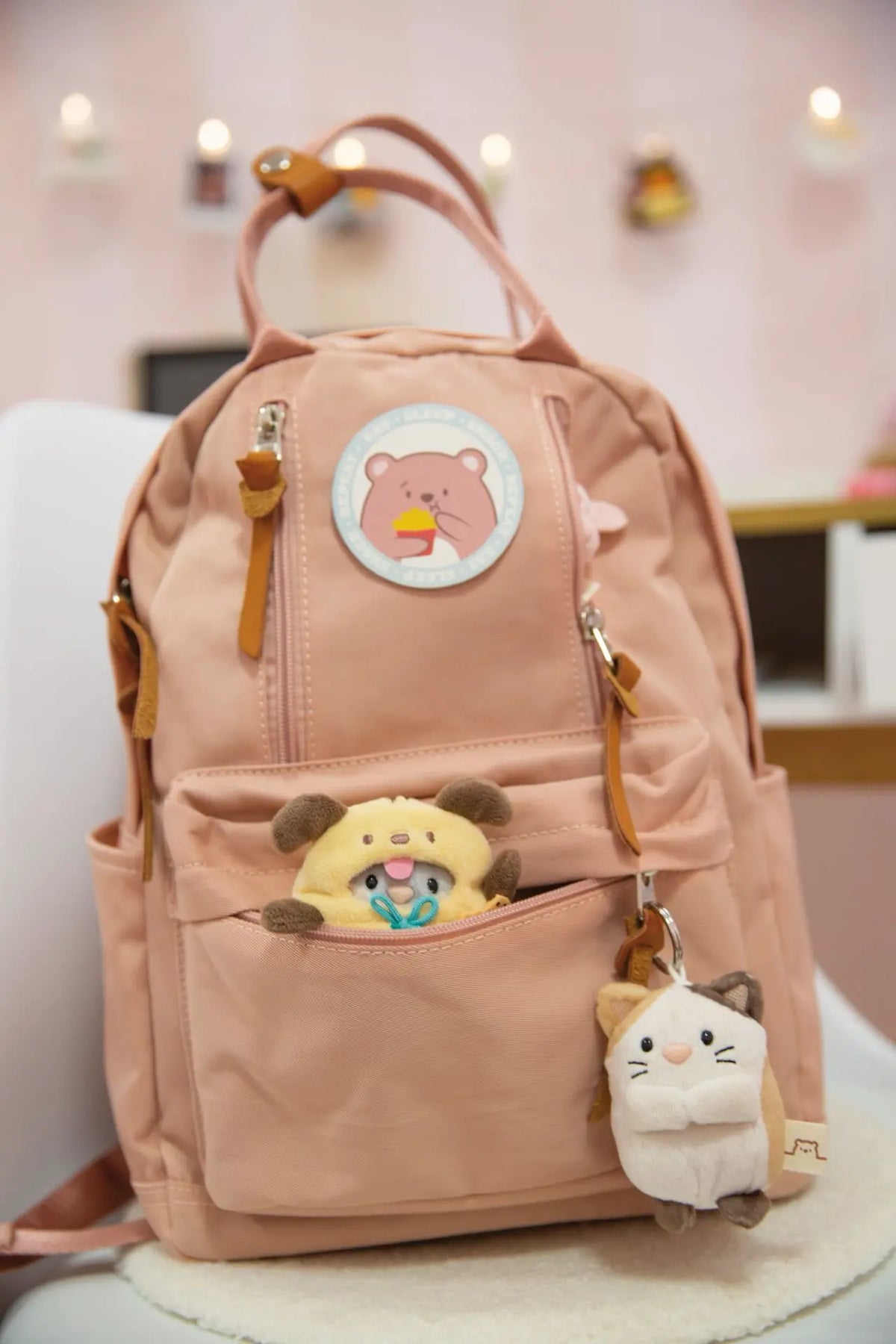 NICI mymochi Plüschkatze als Schlüsselanhänger an einem rosa Kinderrucksack mit weiteren Kuscheltieren
