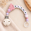 Personalisierte Schnullerkette mit Namen Eltina und Schmetterlingsmotiv in Rosa und Flieder. Handgefertigte Schnullerkette von BabyLions® mit Silikonperlen, Häkelperle, Holzclip und Schnullerring – individuelles Geschenk zur Geburt.
