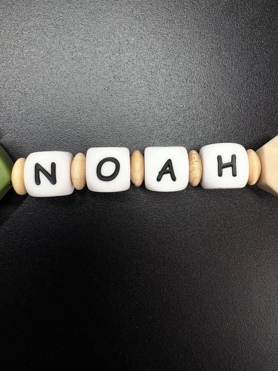 Namensperlen Noah auf personalisierter Schnullerkette in Grün mit Holzringen und Silikonperlen