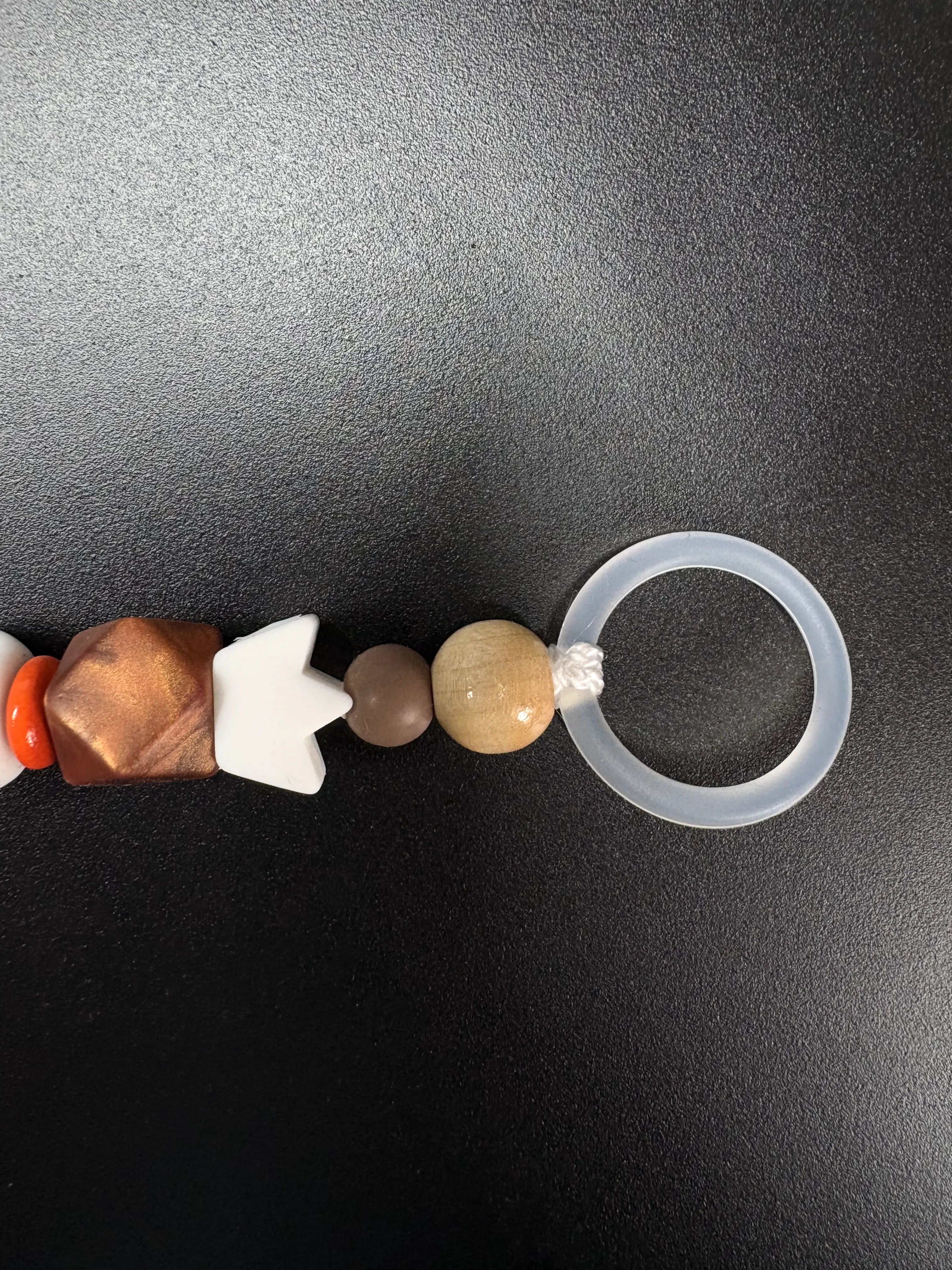 Detail der personalisierten Schnullerkette Simba mit Silikonring, braunen Holzperlen und orangefarbenen Akzenten