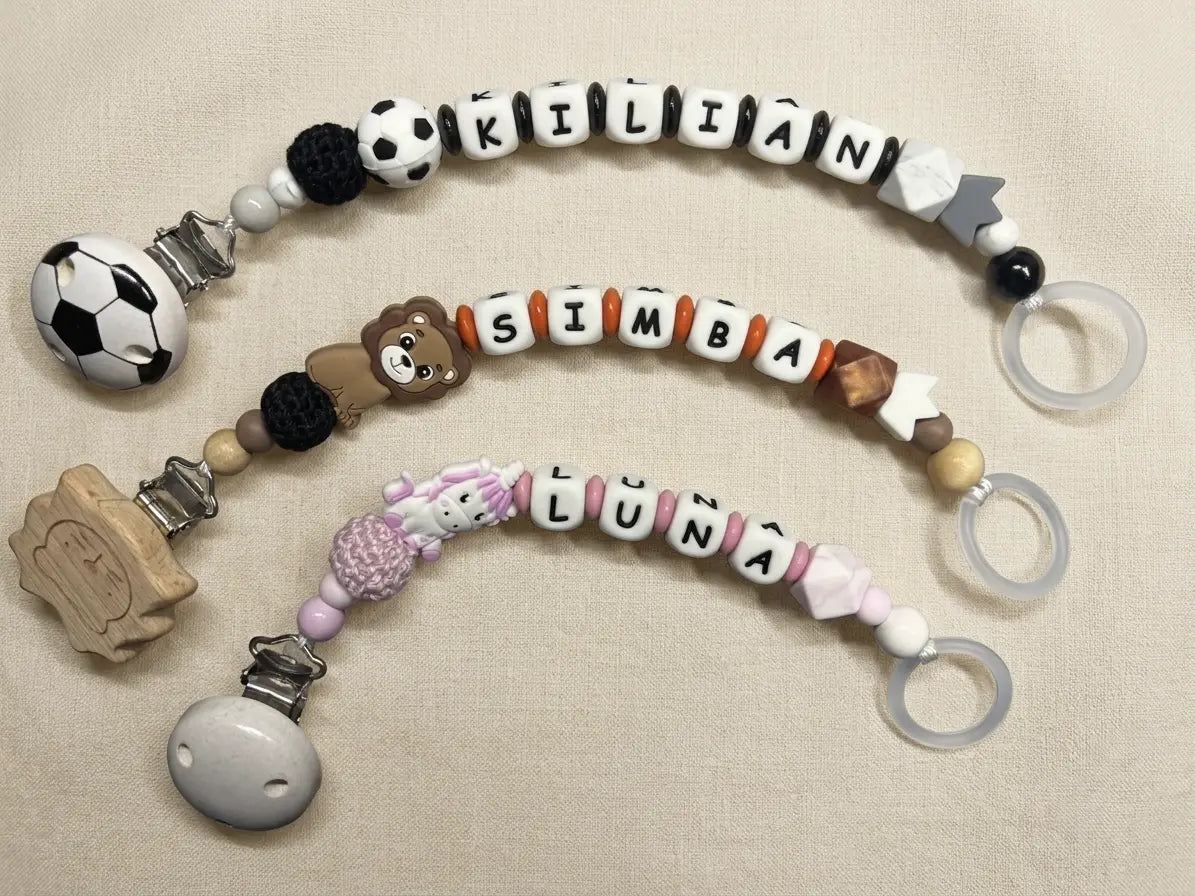 Drei handgemachte personalisierte Schnullerketten von BabyLions® mit den Namen Kilian, Simba und Luna auf hellem Hintergrund