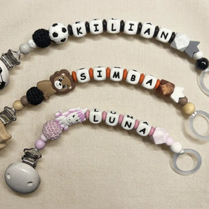 Drei handgemachte personalisierte Schnullerketten von BabyLions® mit den Namen Kilian, Simba und Luna auf hellem Hintergrund